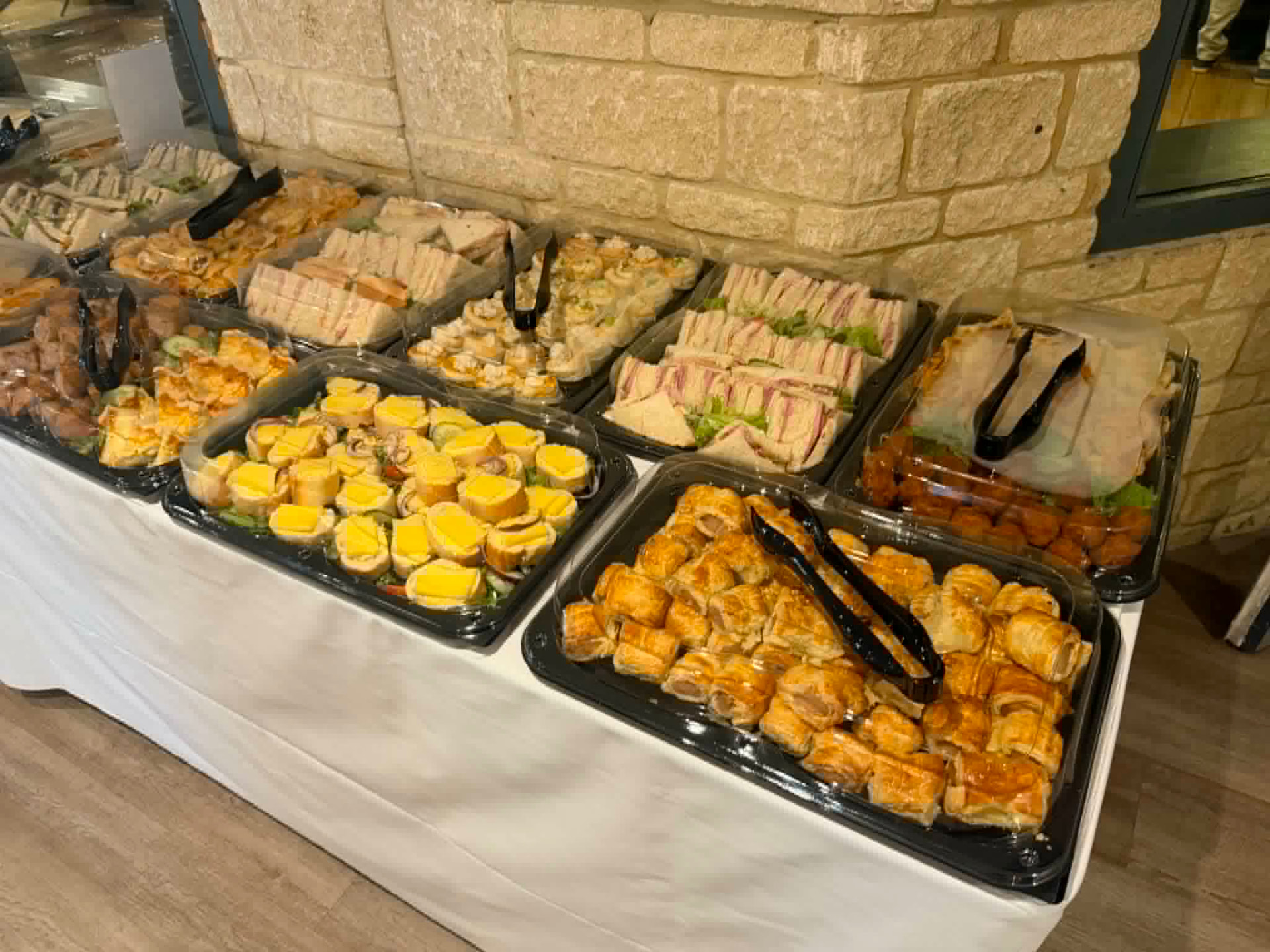Sandwich platters, sausage rolls and savouries with serving tongs